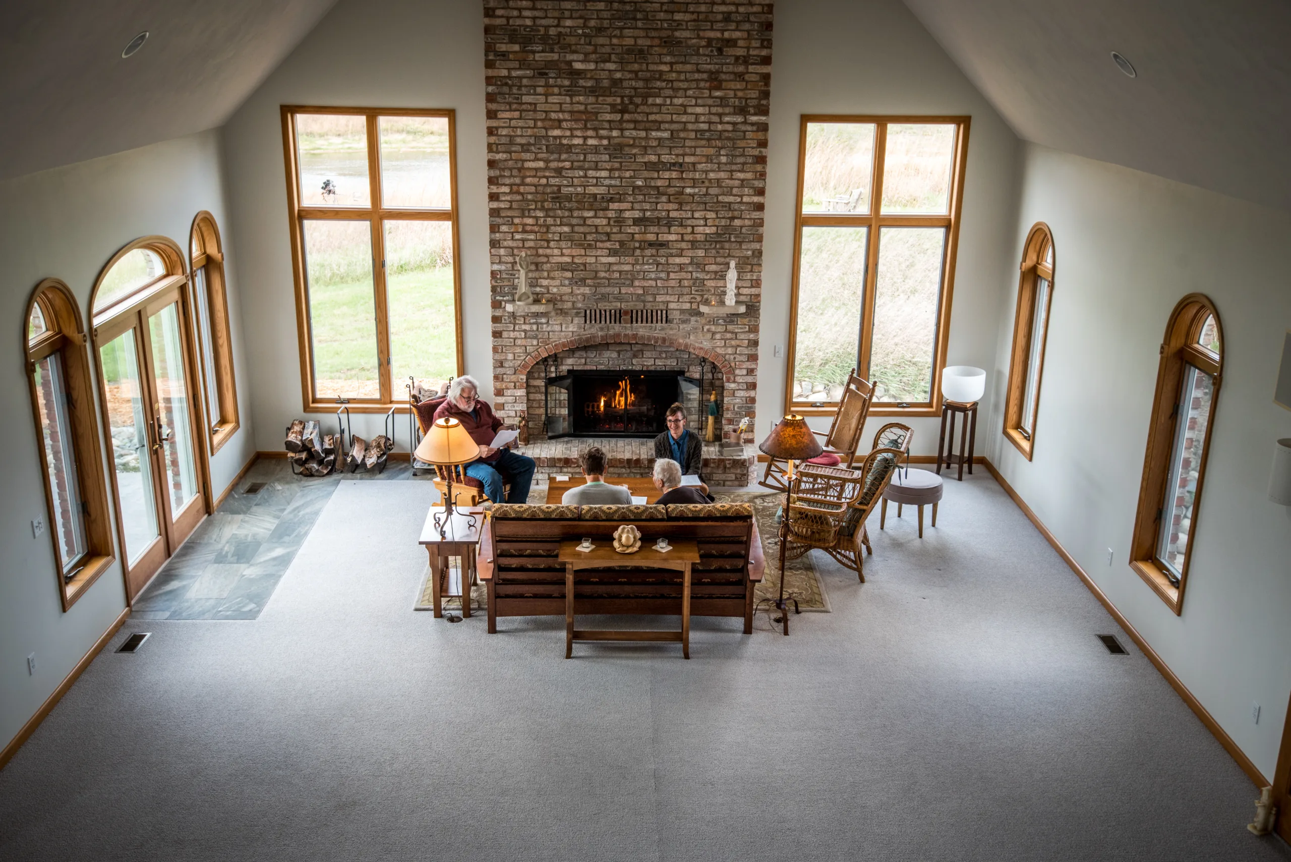 Small group gathers in large room by fireplace