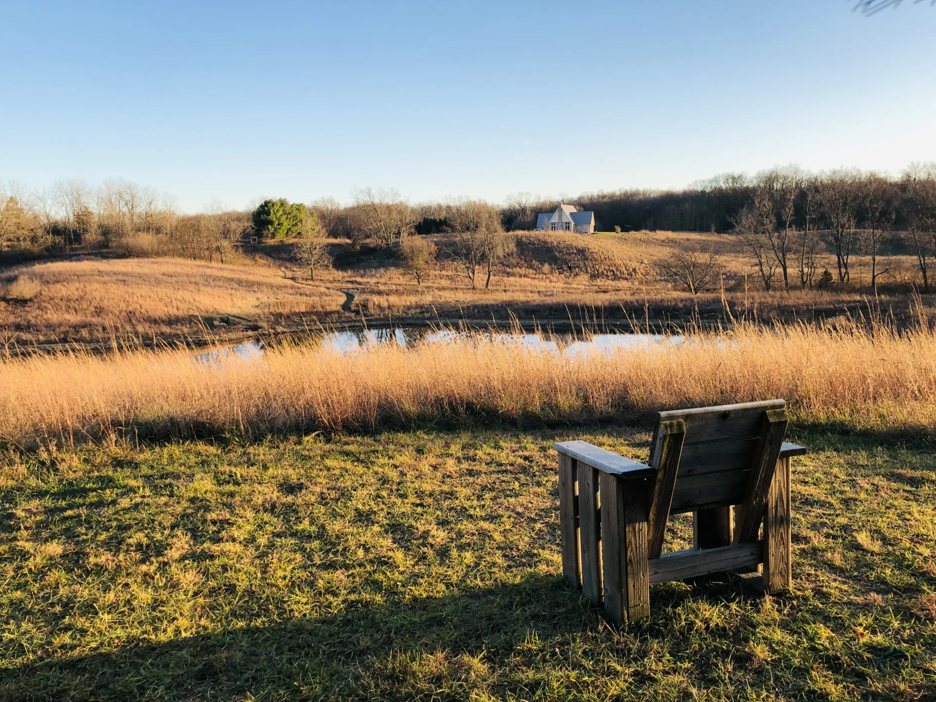 empty wooden chair looking over pond and prairie in fall/autumn