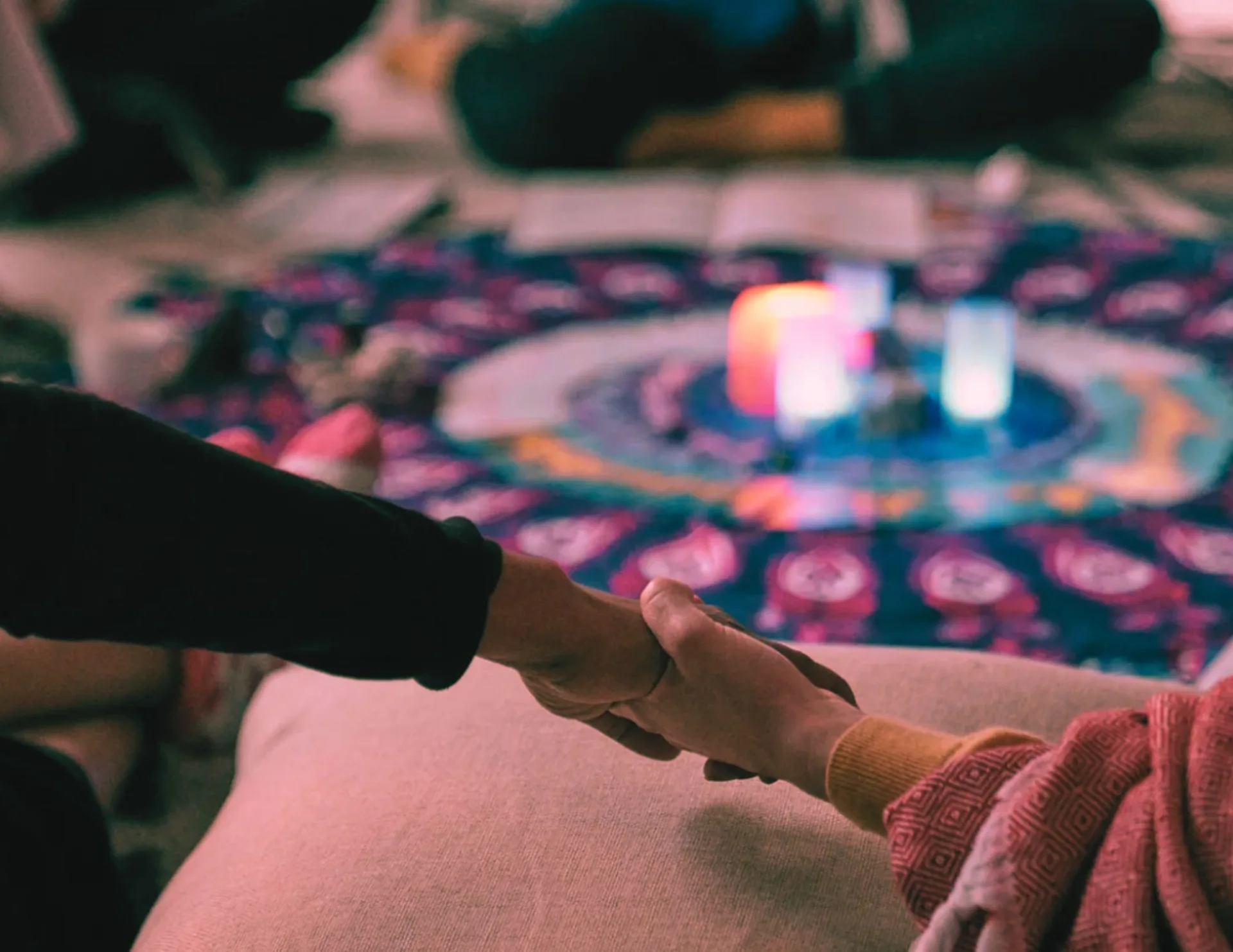 two people holding hands around a circle with candles in the middle