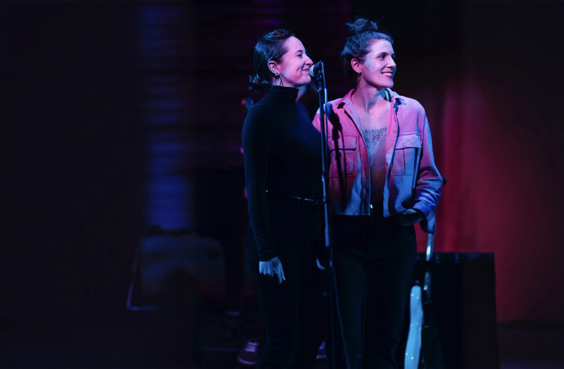 Two women standing at a microphone and smiling